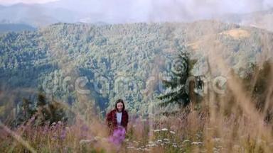 快乐微笑<strong>的</strong>黑发女子旅行者正在喀尔巴阡山徒步旅行。 在花、麦穗和g间<strong>行走的</strong>女游客